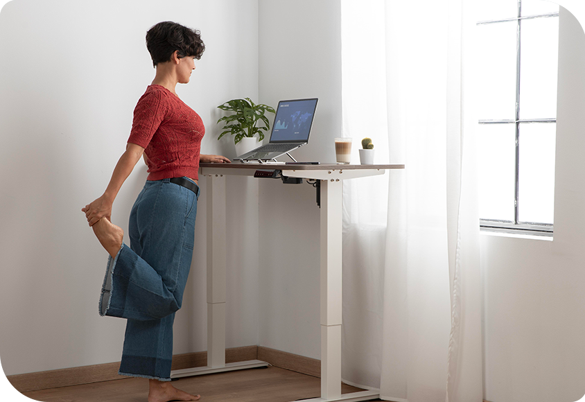 Femme faisant des étirements devant un bureau ergonomique pour avoir une bonne posture de travail